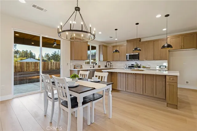 a kitchen with stainless steel appliances kitchen island granite countertop a table chairs and a refrigerator