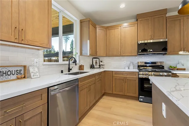 a kitchen with stainless steel appliances granite countertop a sink a stove and a wooden floors