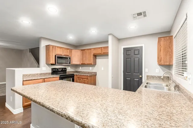 a kitchen with stainless steel appliances granite countertop a refrigerator sink and stove