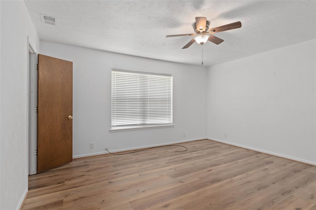 301 East 6th Street Krum, TX 76249 - Photo 17 of 29 Bedroom featuring wood-like flooring, ceiling fan and large window allowing in plenty of natural light.