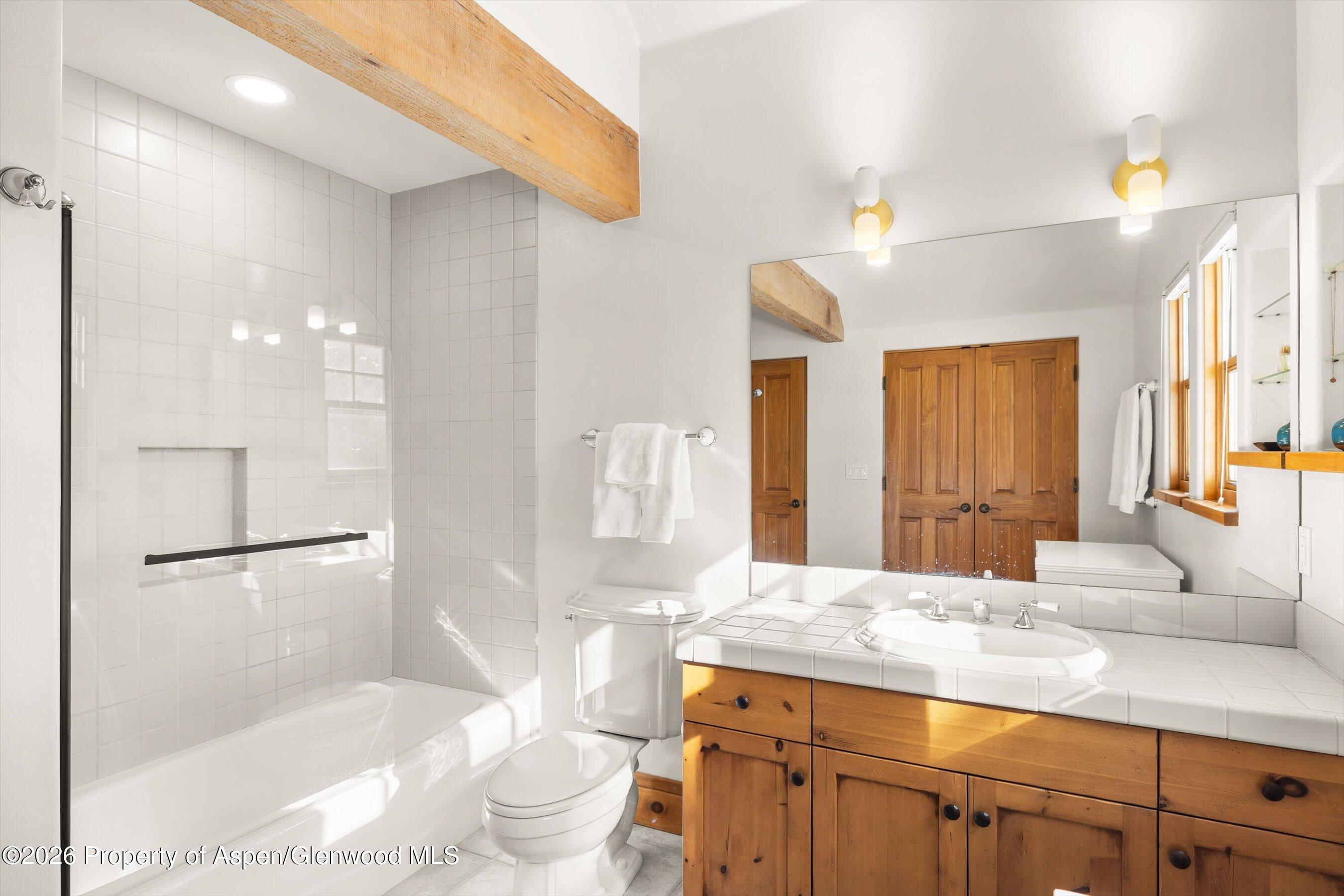 31 Wind River Road Carbondale, CO 81623 - Photo 38 of 46 a bathroom with a granite countertop sink a toilet a mirror and shower
