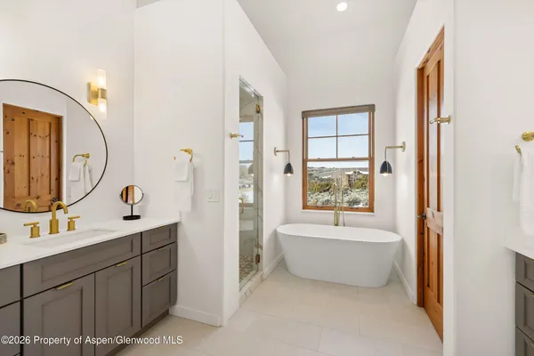 a large white kitchen with kitchen island granite countertop a large window