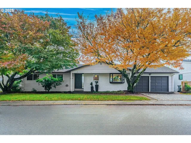 a view of a house with a big yard and large trees