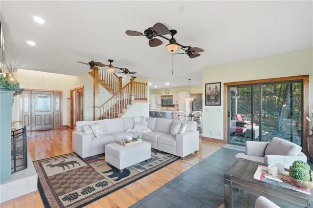 a kitchen with stainless steel appliances kitchen island granite countertop a refrigerator a stove a dining table and chairs with wooden floor