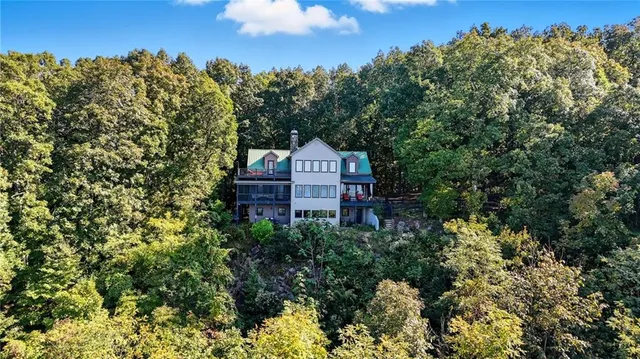 a view of a house with a yard and large trees