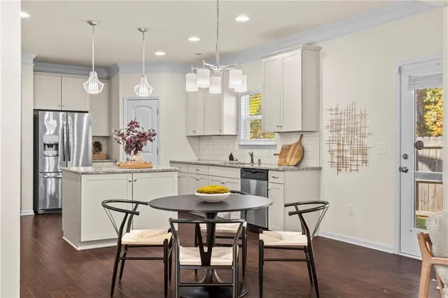 a kitchen with stainless steel appliances a dining table chairs refrigerator and sink