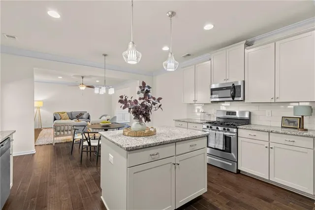 a kitchen with a sink stove and white cabinets with wooden floor