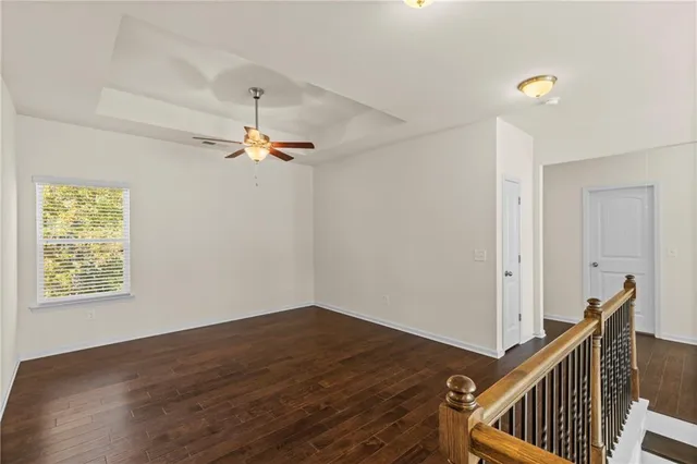 an empty room with wooden floor ceiling fan and windows
