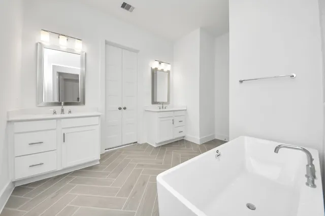 a bathroom with a sink vanity granite tub and a mirror