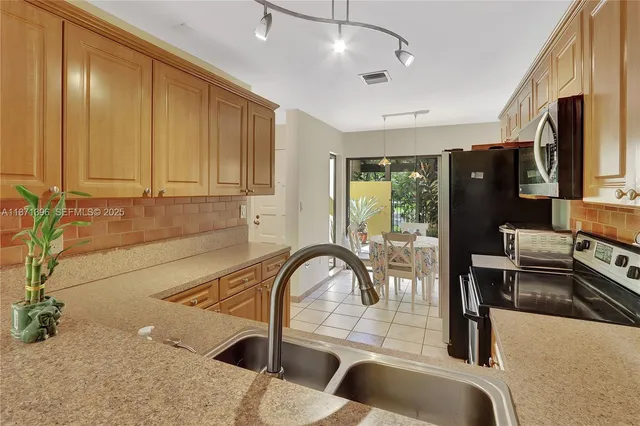 a kitchen with stainless steel appliances granite countertop a sink a stove and a refrigerator