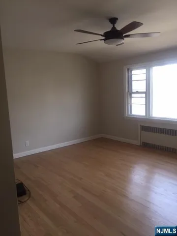 an empty room with wooden floor fan and windows