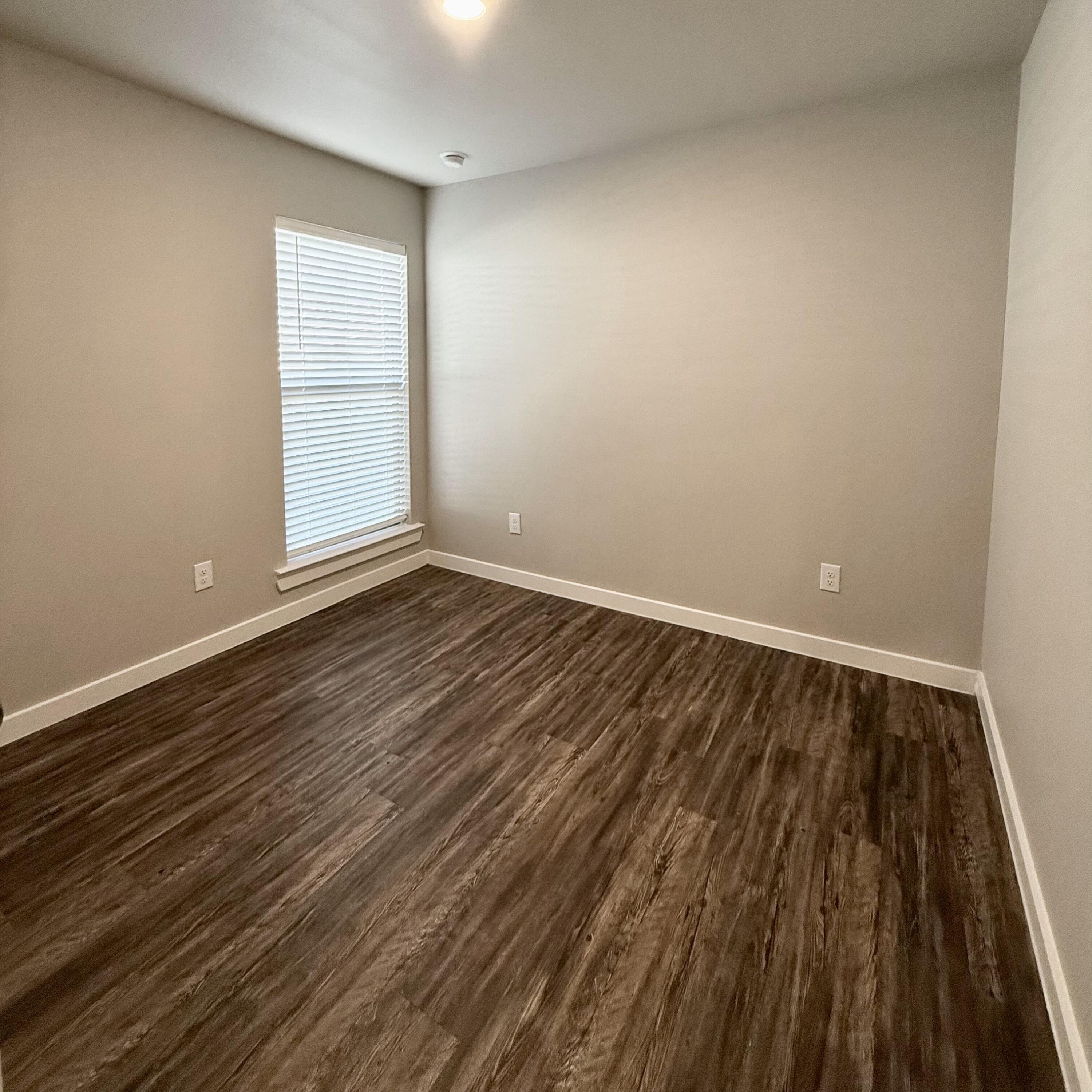 2108 North Jayton Avenue, Unit A Lubbock, TX 79403 - Photo 13 of 17 an empty room with wooden floor and windows