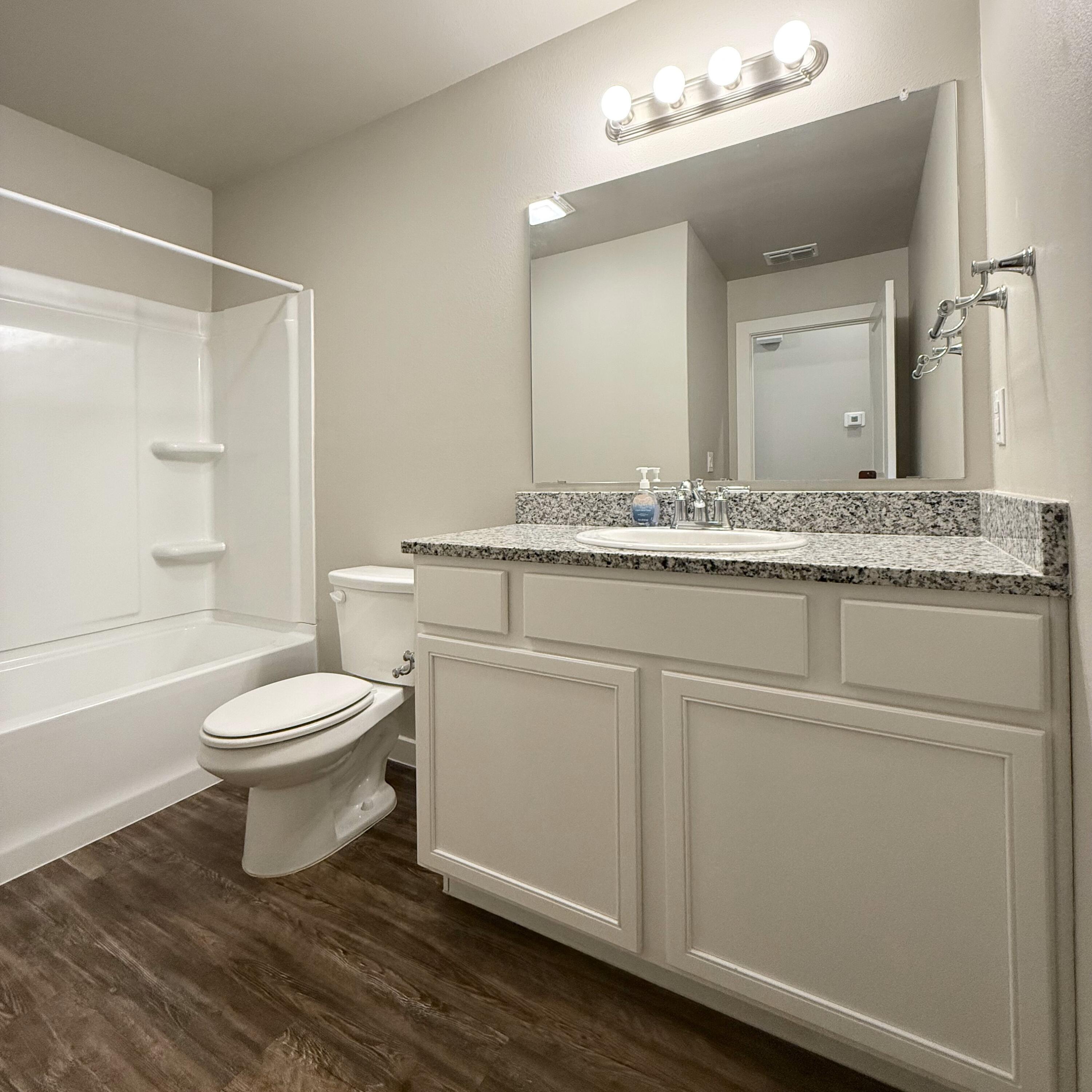 2108 North Jayton Avenue, Unit A Lubbock, TX 79403 - Photo 15 of 17 a bathroom with a granite countertop toilet a sink and a mirror