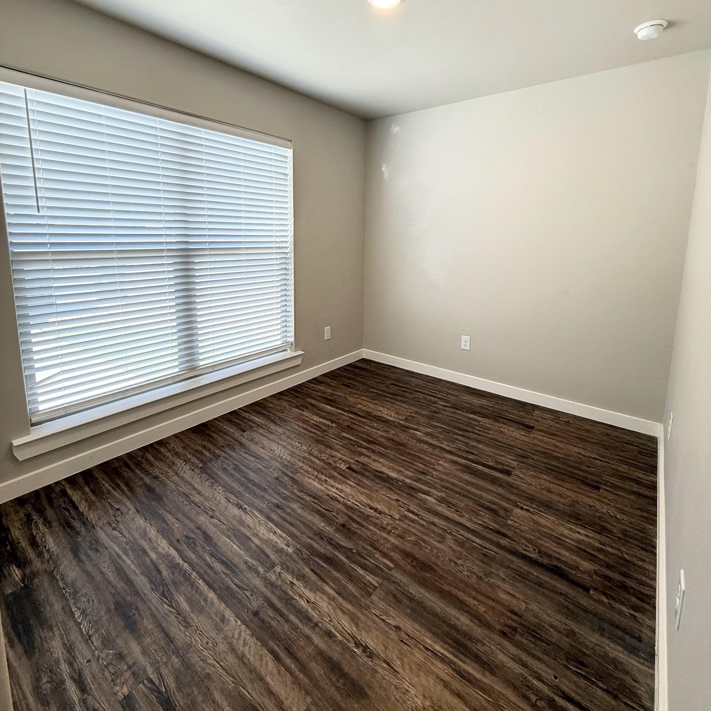 2108 North Jayton Avenue, Unit A Lubbock, TX 79403 - Photo 16 of 17 a view of an empty room with wooden floor and a window