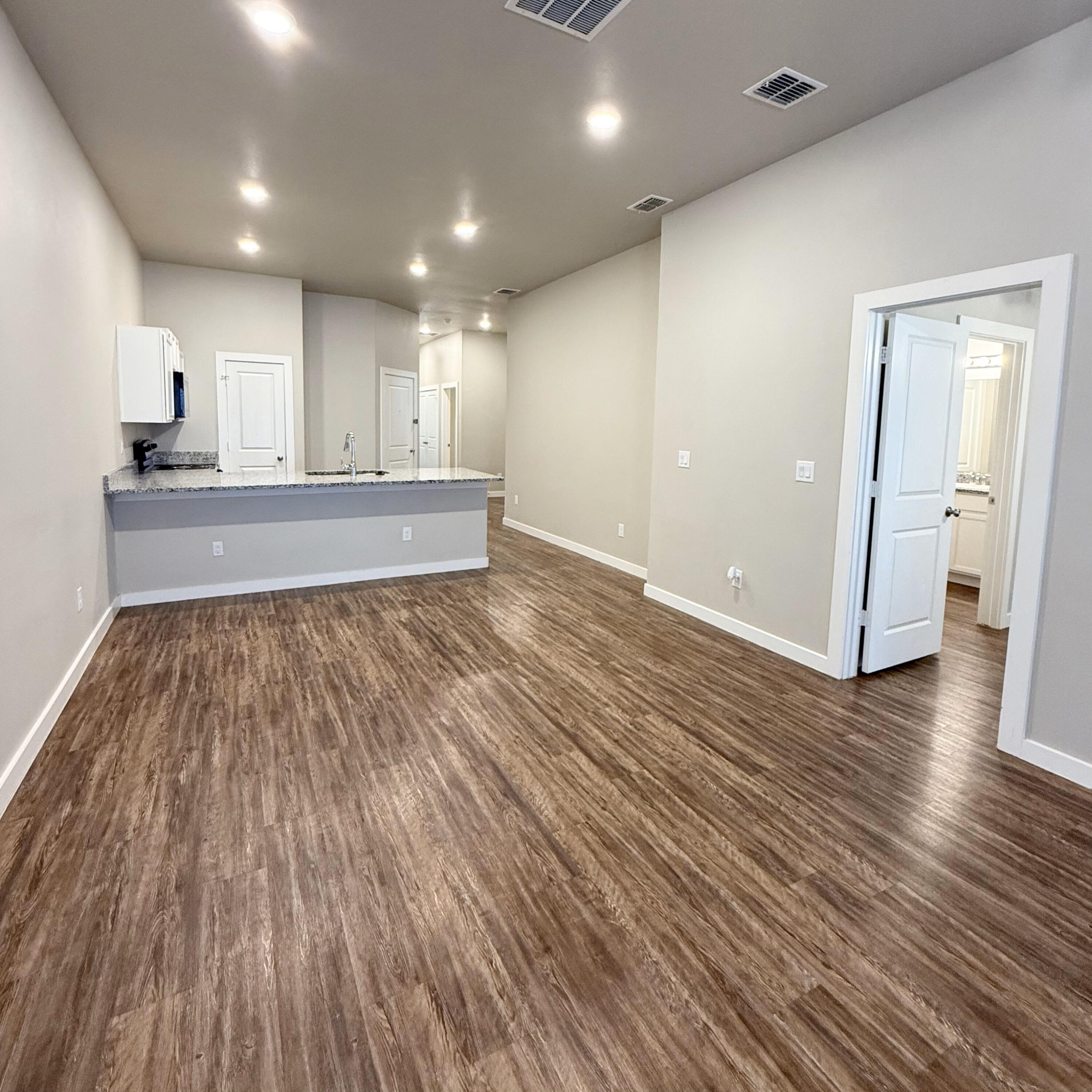 2108 North Jayton Avenue, Unit A Lubbock, TX 79403 - Photo 6 of 17 a view of an empty room with wooden floor and a kitchen