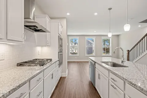 a kitchen with granite countertop a sink a counter space appliances and cabinets