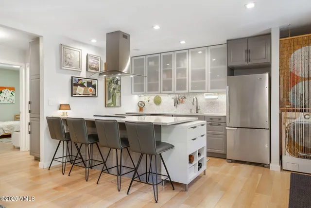 a kitchen with stainless steel appliances a dining table chairs refrigerator and sink