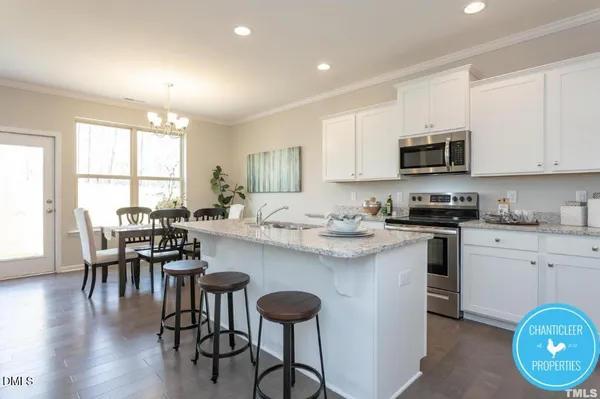 a kitchen with stainless steel appliances granite countertop a stove a sink a microwave a dining table and chairs with wooden floor