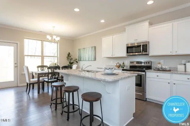 a kitchen with stainless steel appliances granite countertop a stove a sink a microwave a dining table and chairs with wooden floor