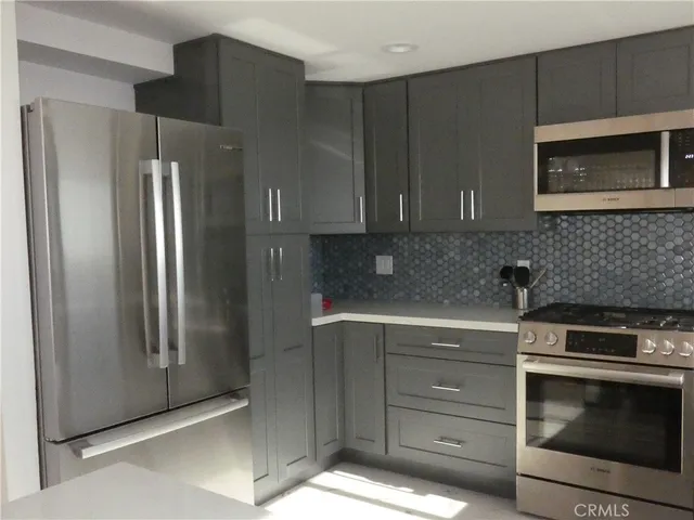 a kitchen with stainless steel appliances granite countertop a refrigerator and a stove top oven