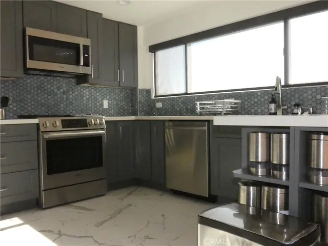 a kitchen with stainless steel appliances granite countertop a stove a sink and a microwave