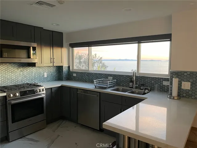 a kitchen with stainless steel appliances kitchen island granite countertop a stove a sink and a microwave