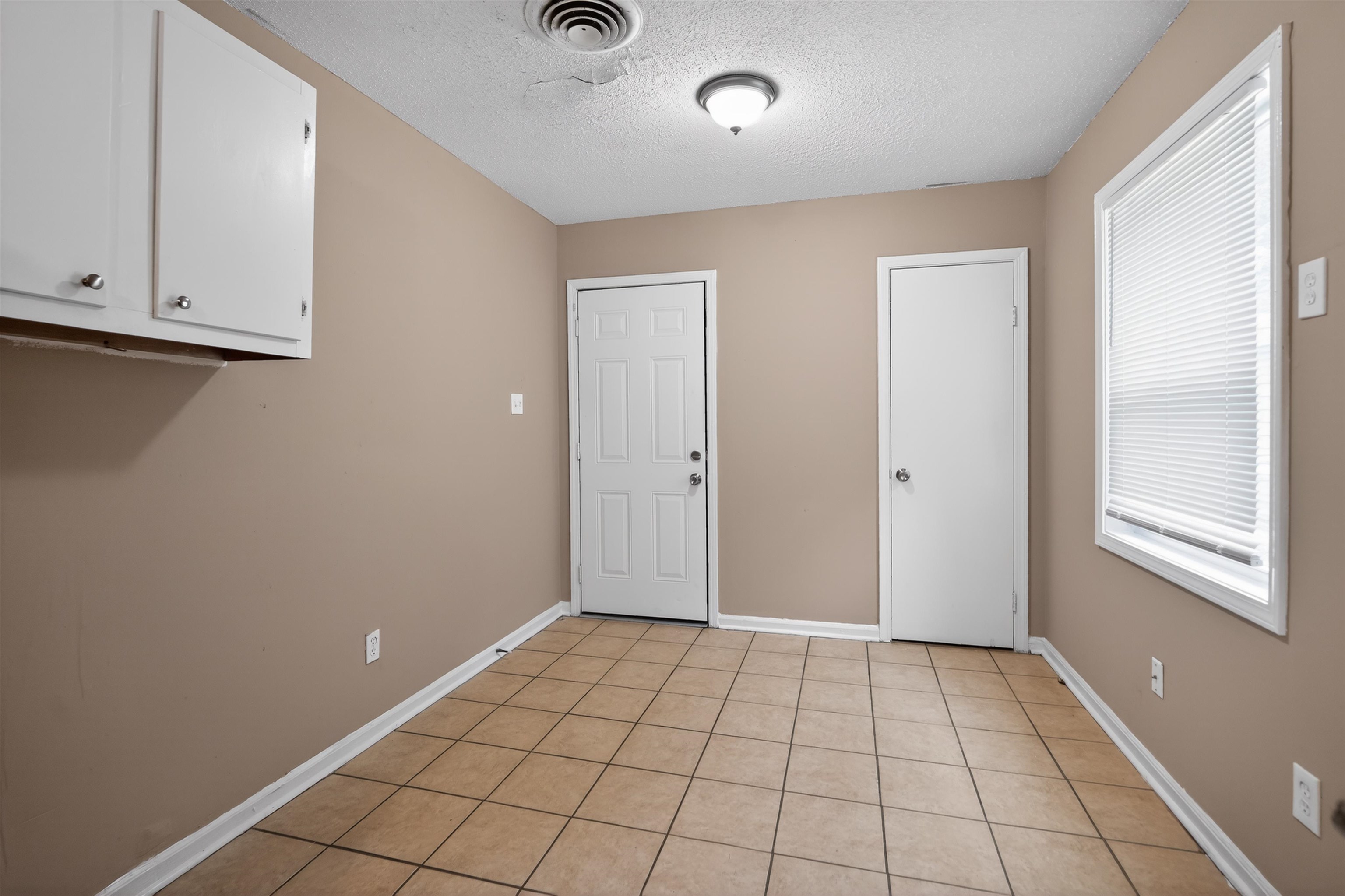 3608 Cane Ridge Drive Memphis, TN 38109 - Photo 30 of 31 Tile flooring, neutral wall paint, two white doors, white window blinds, and white upper cabinetry