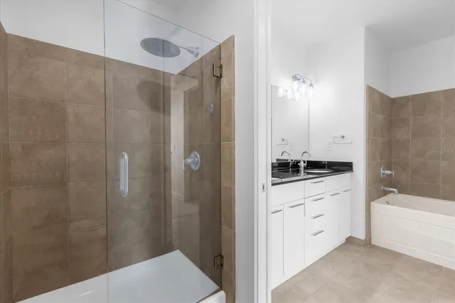 a bathroom with a tub shower sink vanity granite and a shower