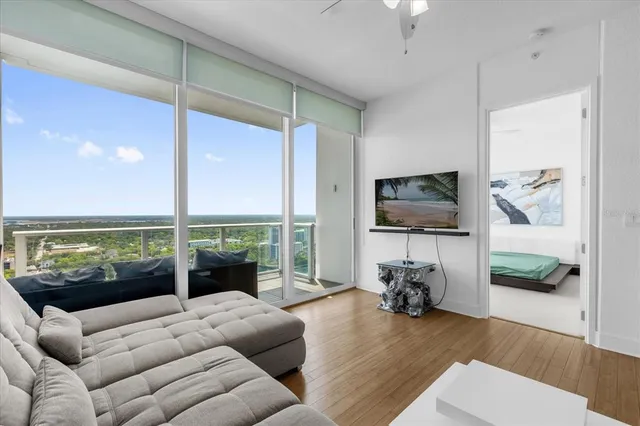 a living room with furniture tv and a floor to ceiling window