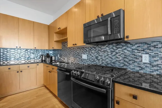 a kitchen with stainless steel appliances granite countertop a stove a sink and a microwave