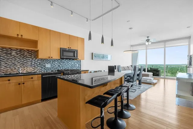 a kitchen with stainless steel appliances granite countertop a stove a sink dishwasher and white cabinets with wooden floor