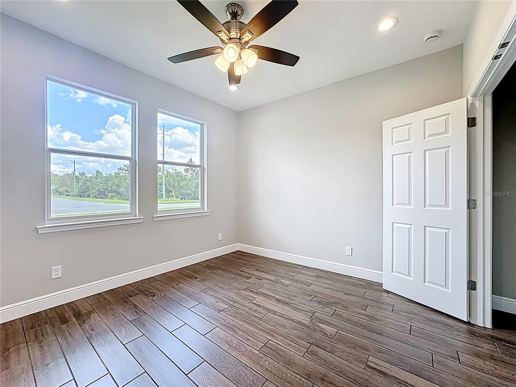 19424 Oakleaf Street Orlando, FL 32833 - Photo 16 of 43 an empty room with wooden floor chandelier fan and windows