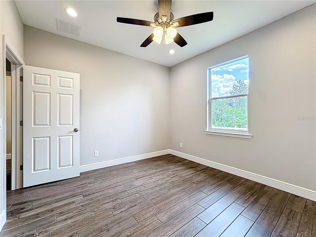 19424 Oakleaf Street Orlando, FL 32833 - Photo 20 of 43 an empty room with wooden floor chandelier fan and windows