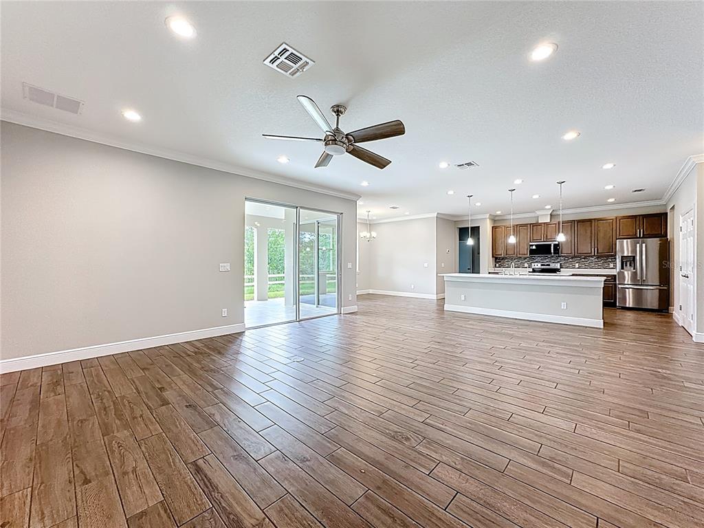 19424 Oakleaf Street Orlando, FL 32833 - Photo 7 of 43 a view of an empty room with wooden floor and a kitchen