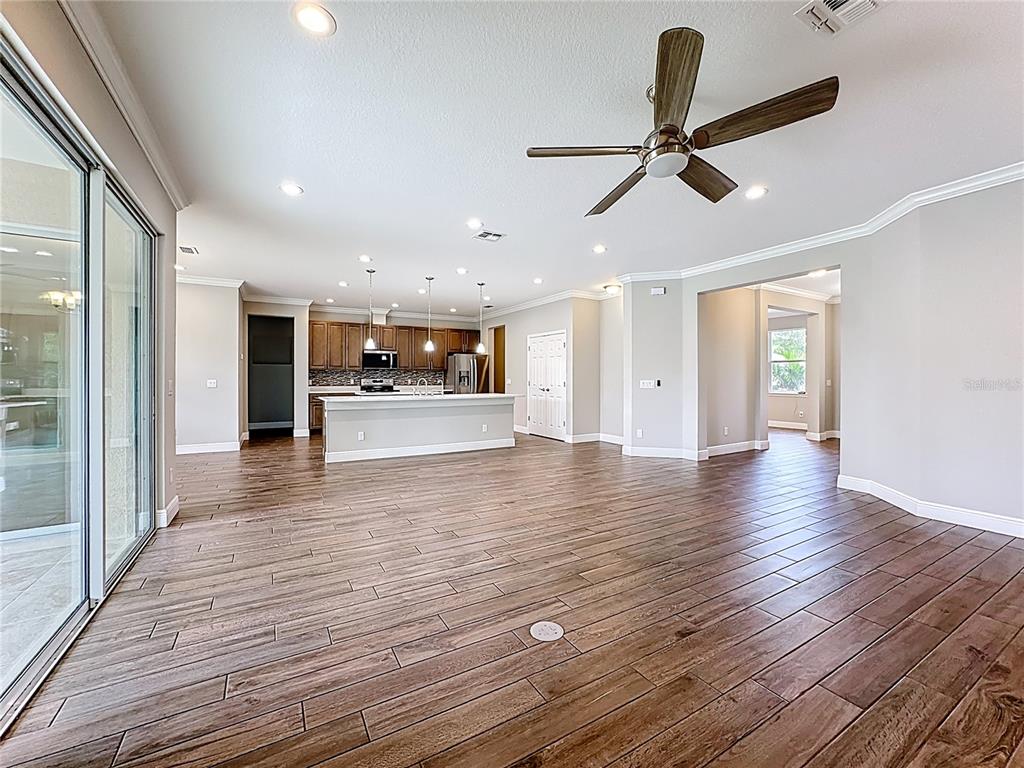 19424 Oakleaf Street Orlando, FL 32833 - Photo 8 of 43 a view of an empty room and kitchen with wooden floor