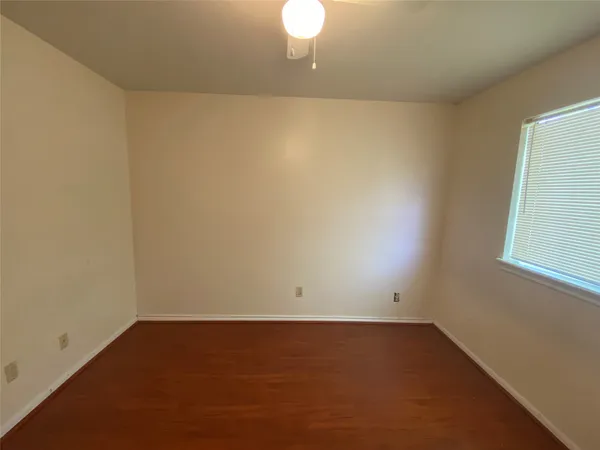 an empty room with a ceiling fan and wooden floor