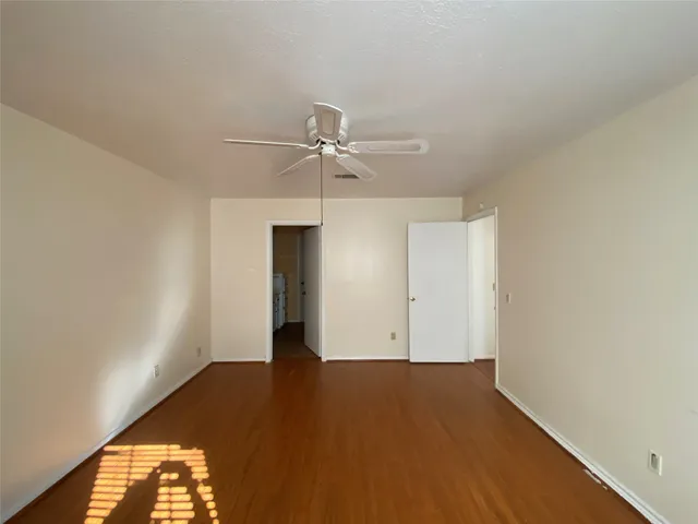 an empty room with a ceiling fan and wooden floor