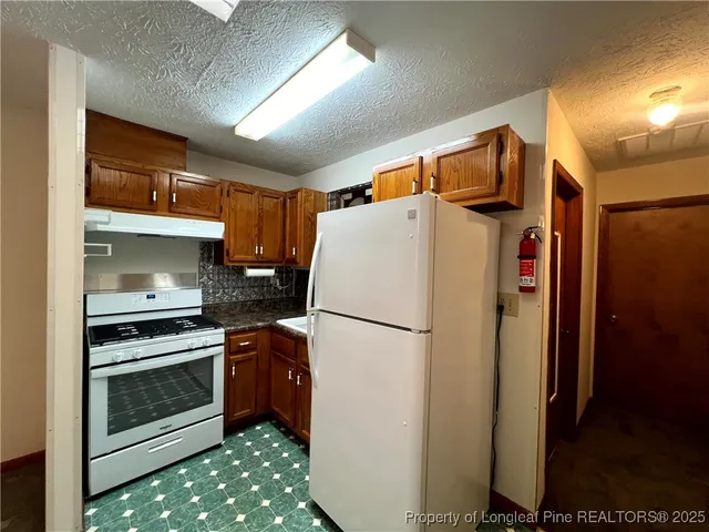 a white refrigerator freezer and a stove sitting inside of a kitchen