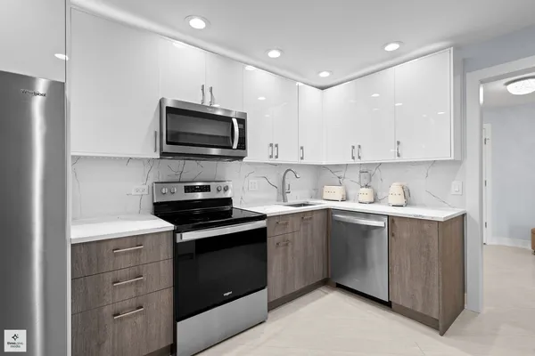 a kitchen with granite countertop white cabinets and stainless steel appliances