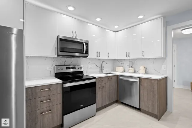 a kitchen with granite countertop white cabinets and stainless steel appliances