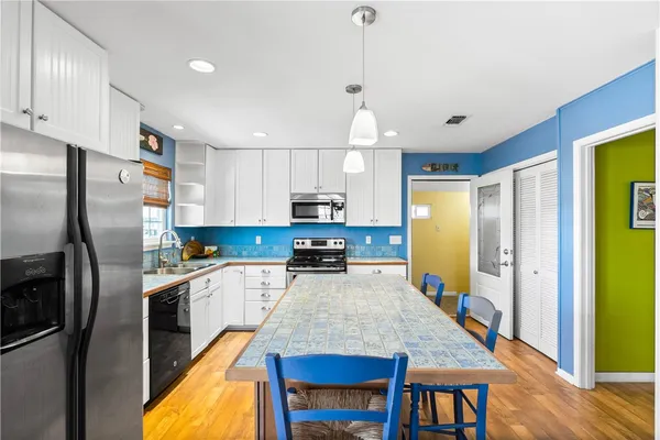 a kitchen with stainless steel appliances granite countertop table chairs stove and refrigerator