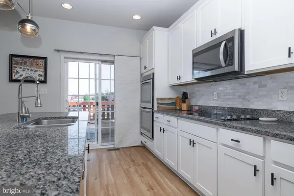 a kitchen with stainless steel appliances granite countertop a stove a sink and a microwave