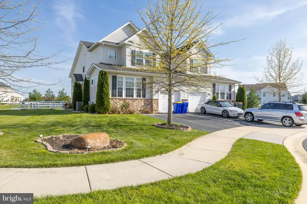 a view of a white house with a yard table and chairs