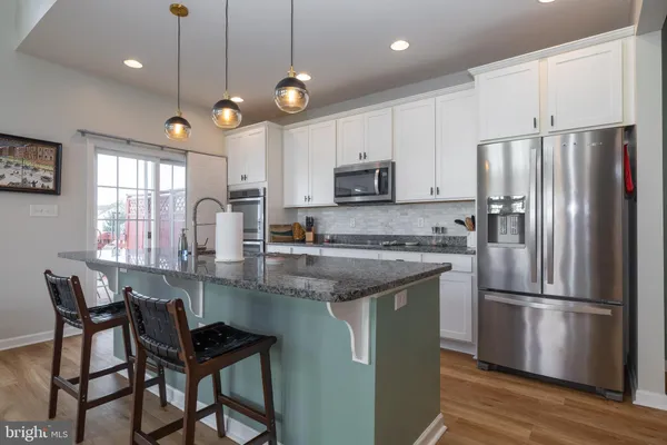 a kitchen with kitchen island granite countertop a sink a center island and stainless steel appliances