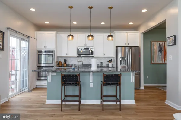 a kitchen with stainless steel appliances granite countertop a refrigerator a stove microwave and island with wooden floor