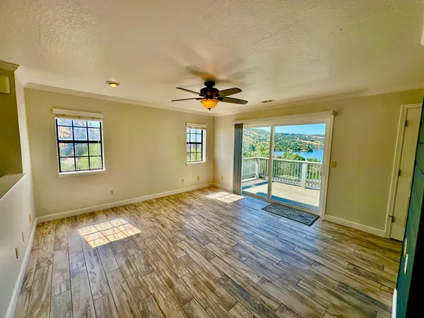 a view of an empty room with a window and wooden floor