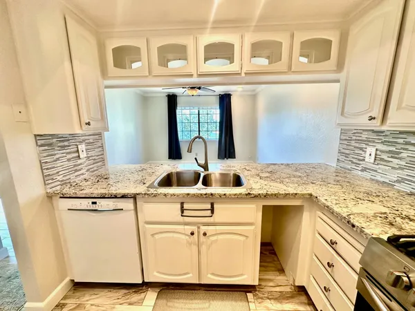 a white kitchen with granite countertop a sink and white cabinets