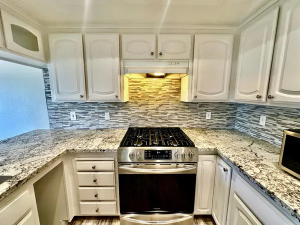 a kitchen with granite countertop a stove sink and cabinets