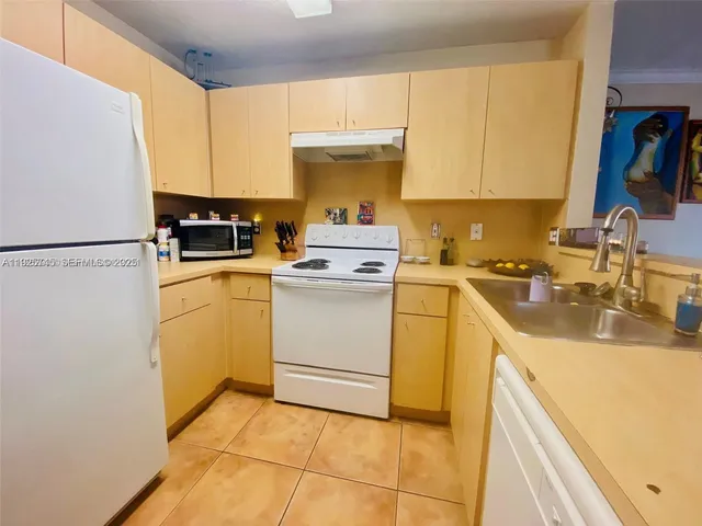 a kitchen with a sink a stove top oven and white refrigerator