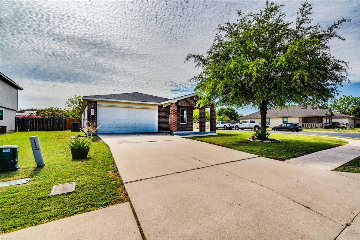 100 Easy Street Hutto, TX 78634 - Photo 34 of 36 A well-kept front yard welcomes with a generous driveway and a mature shade tree.